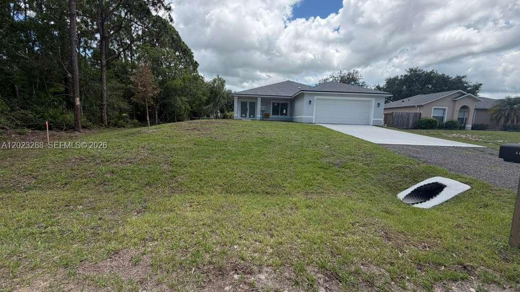 A single-story house with a white garage and a concrete driveway sits on a lawn — 8636 100th Ct, Vero Beach FL 32967, VERO BEACH, FL