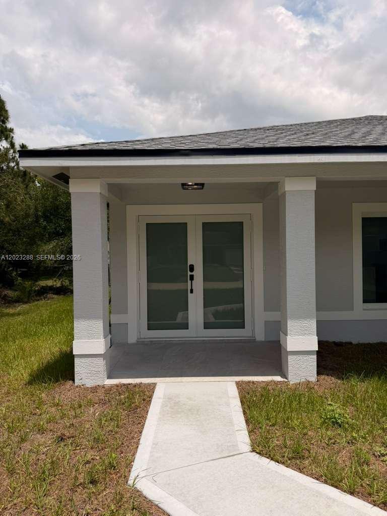 A gray house exterior features a covered porch with double glass doors and a walkway — 8636 100th Ct, Vero Beach FL 32967, VERO BEACH, FL