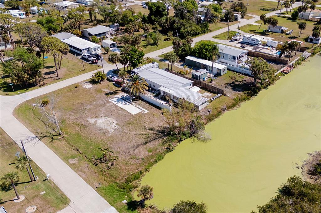 An aerial view shows a mobile home on a waterfront lot with a large yard — 8195 PINE TREE LANE, ENGLEWOOD, FL