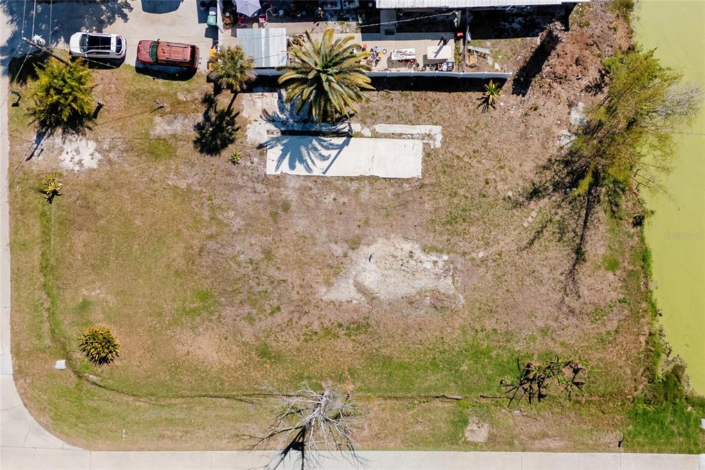 An aerial view shows a vacant residential lot with a concrete slab and palm trees — 8195 PINE TREE LANE, ENGLEWOOD, FL