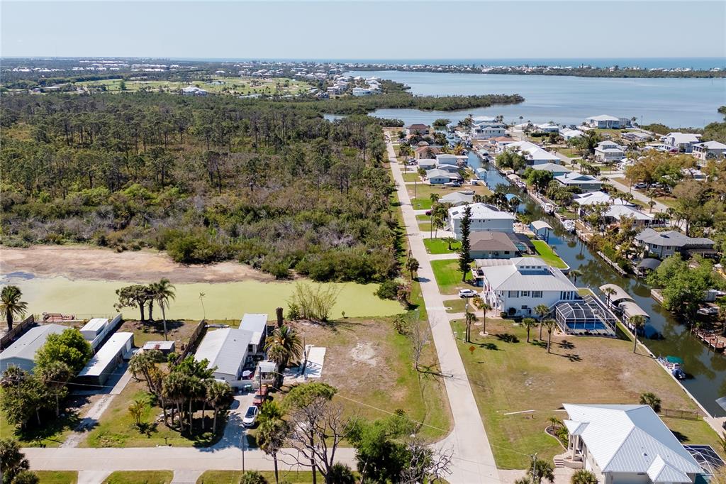An aerial view shows a residential street lined with houses, a canal, and wooded areas — 8195 PINE TREE LANE, ENGLEWOOD, FL