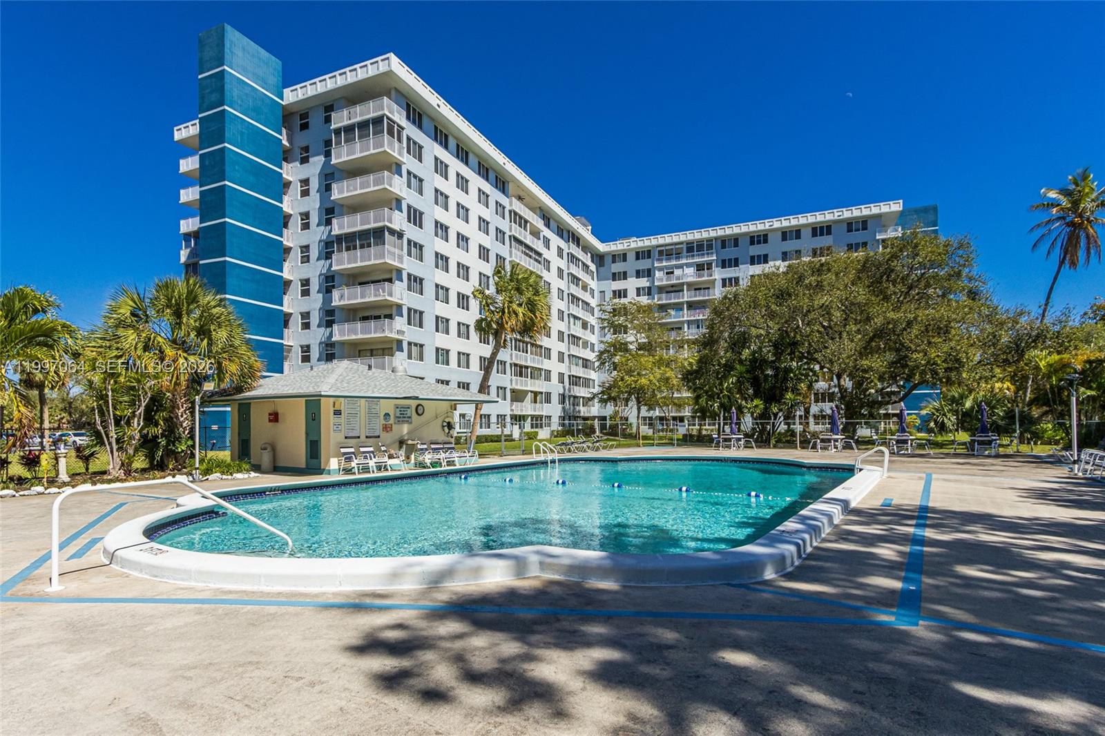 A swimming pool sits in front of a large, multi-story apartment building with balconies — 4200 Hillcrest Dr # 408, Hollywood FL 33021, HOLLYWOOD, FL