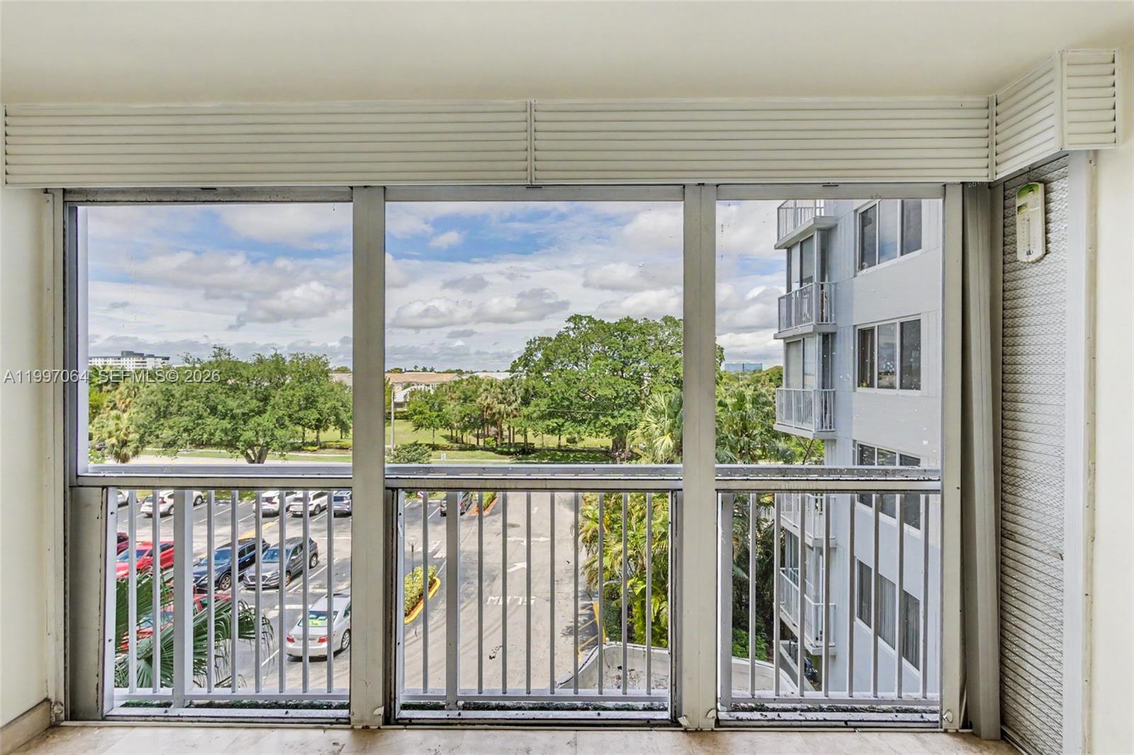 A view from a balcony looking out over a parking lot and green trees — 4200 Hillcrest Dr # 408, Hollywood FL 33021, HOLLYWOOD, FL