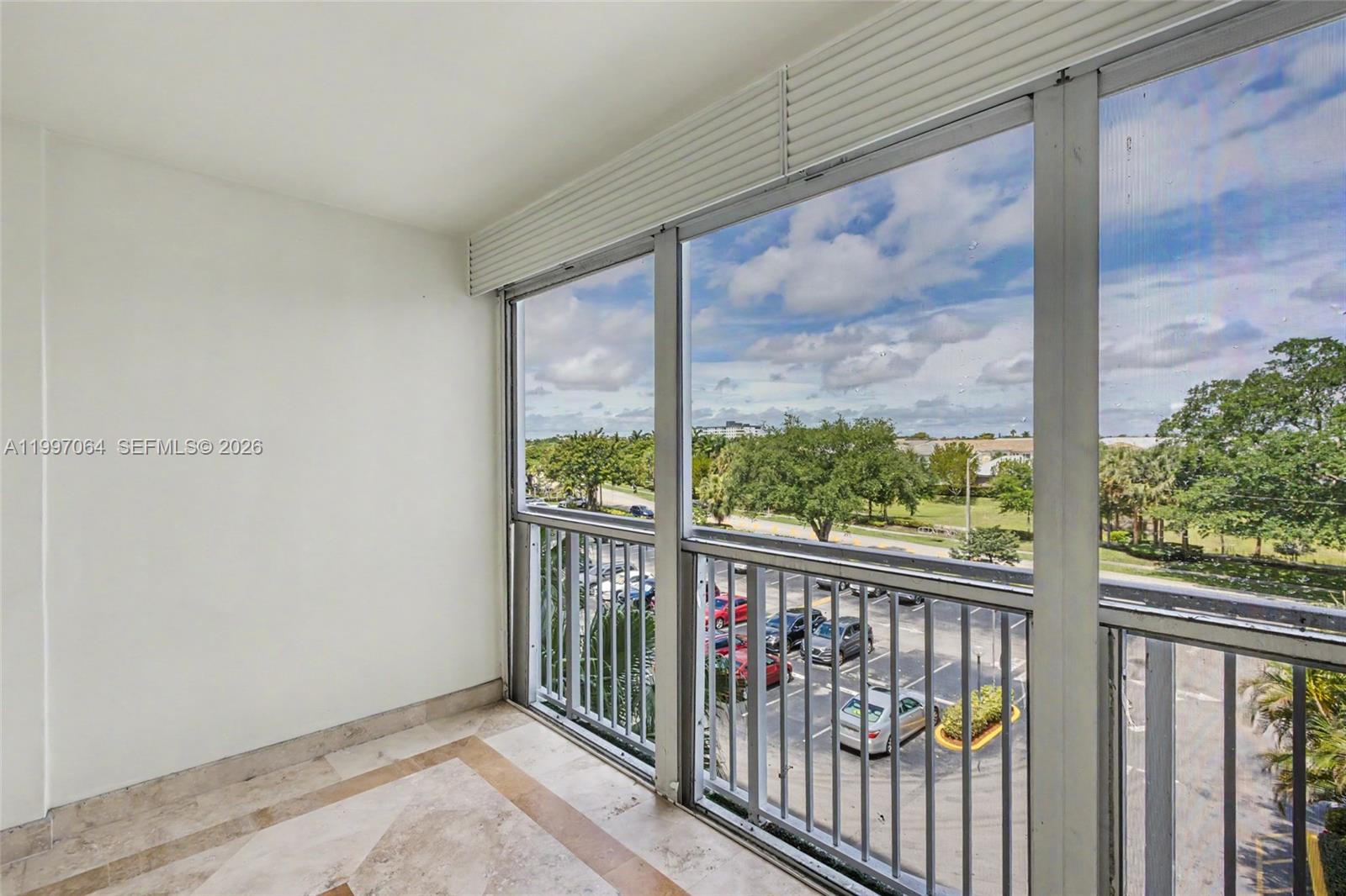 A balcony with tile flooring, white walls, and metal railings overlooks a parking lot — 4200 Hillcrest Dr # 408, Hollywood FL 33021, HOLLYWOOD, FL