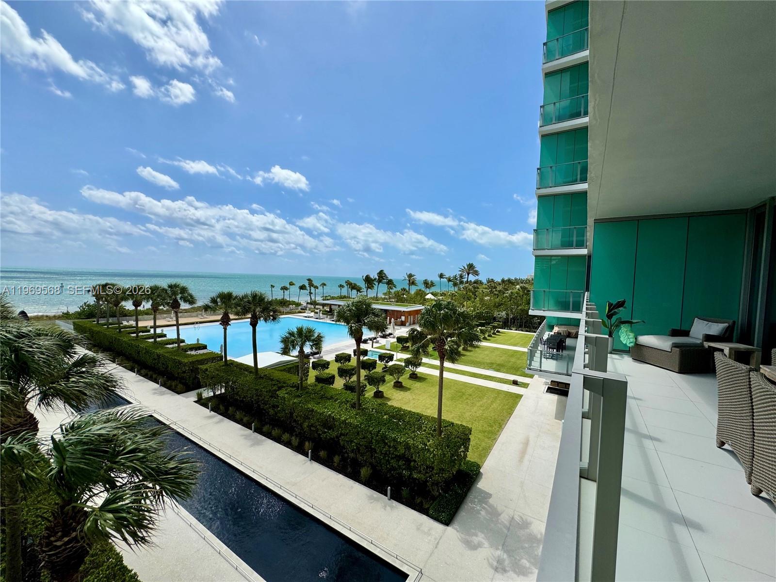 A high-angle view of a balcony overlooking a swimming pool, lawn, and the ocean — 350 Ocean Dr # 406N, Key Biscayne FL 33149, KEY BISCAYNE, FL