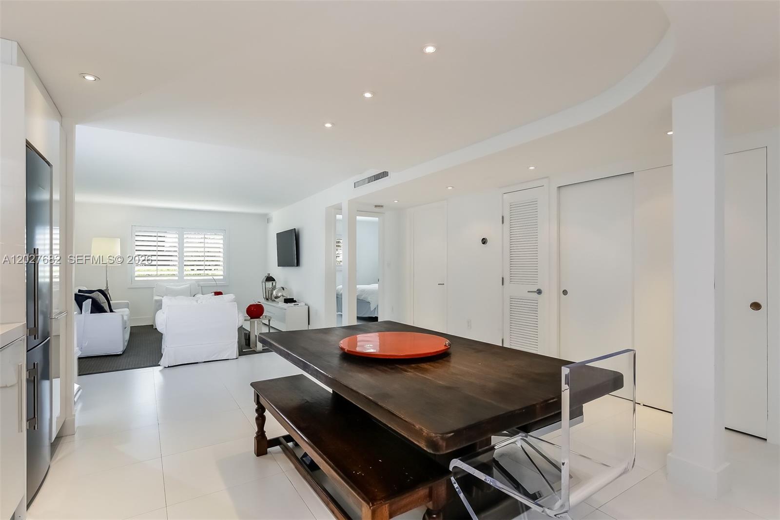 A modern open-concept living and dining area features white tile floors and dark wood furniture — 200 Galen Dr # 104, Key Biscayne FL 33149, KEY BISCAYNE, FL