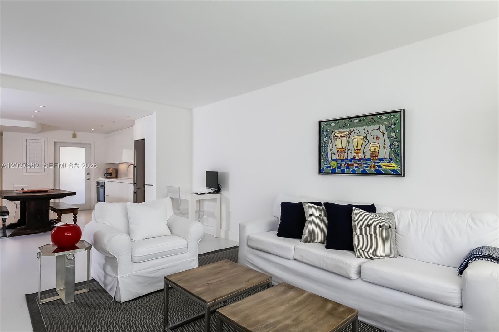A living room features a white sofa, armchair, two coffee tables, and a wall painting — 200 Galen Dr # 104, Key Biscayne FL 33149, KEY BISCAYNE, FL