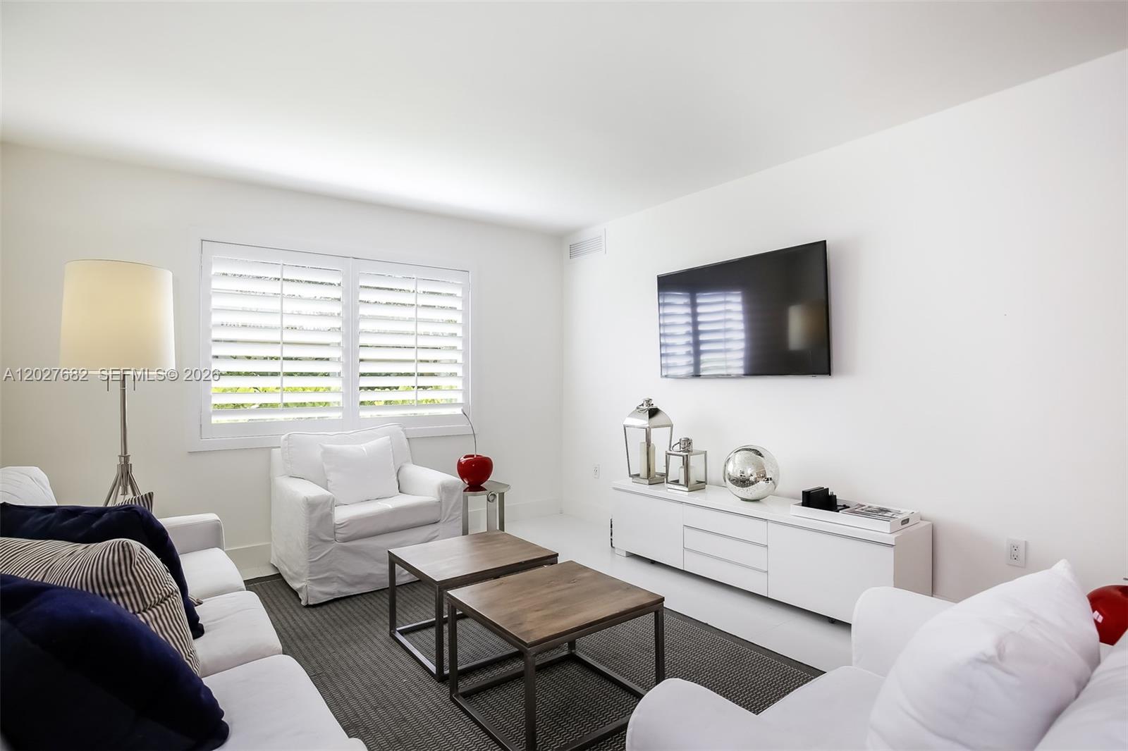 A living room features white furniture, two wooden coffee tables, and a wall-mounted television — 200 Galen Dr # 104, Key Biscayne FL 33149, KEY BISCAYNE, FL