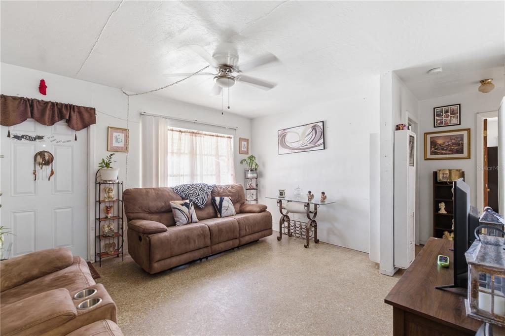 A living room features a brown sofa, a ceiling fan, and a glass-topped console table — 5031 GRAND BOULEVARD, NEW PORT RICHEY, FL