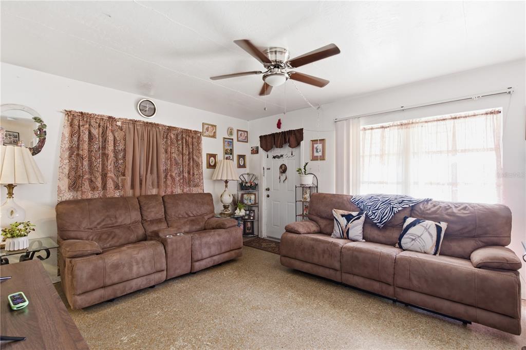 A living room features two brown reclining sofas, a ceiling fan, and a front door — 5031 GRAND BOULEVARD, NEW PORT RICHEY, FL