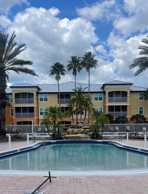A swimming pool with a rock water feature sits in front of a multi-story apartment building — 5467 VINELAND ROAD UNIT 6114, ORLANDO, FL