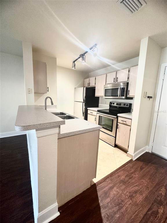 A kitchen features light wood cabinets, stainless steel appliances, and a breakfast bar — 5467 VINELAND ROAD UNIT 6114, ORLANDO, FL