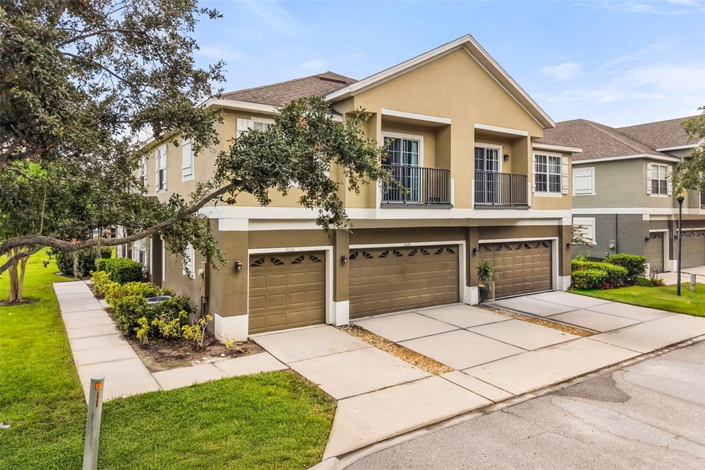 A two-story townhouse exterior with three garage doors and two upper-level balconies — 2026 ESTANCIA CIRCLE UNIT A, KISSIMMEE, FL