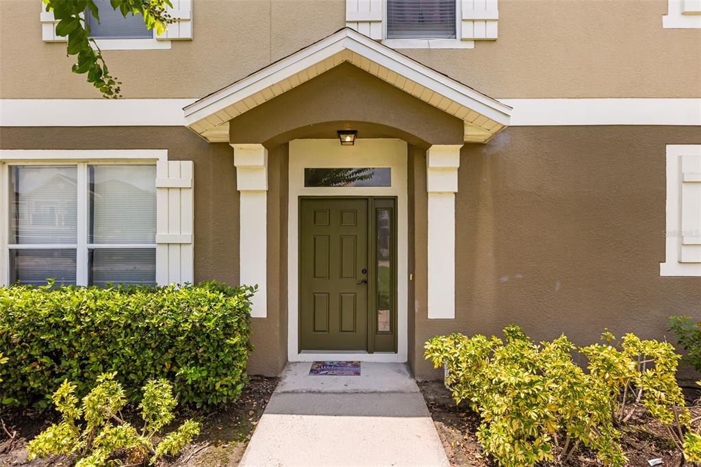 The exterior of a two-story home features a covered entryway with a green front door — 2026 ESTANCIA CIRCLE UNIT A, KISSIMMEE, FL