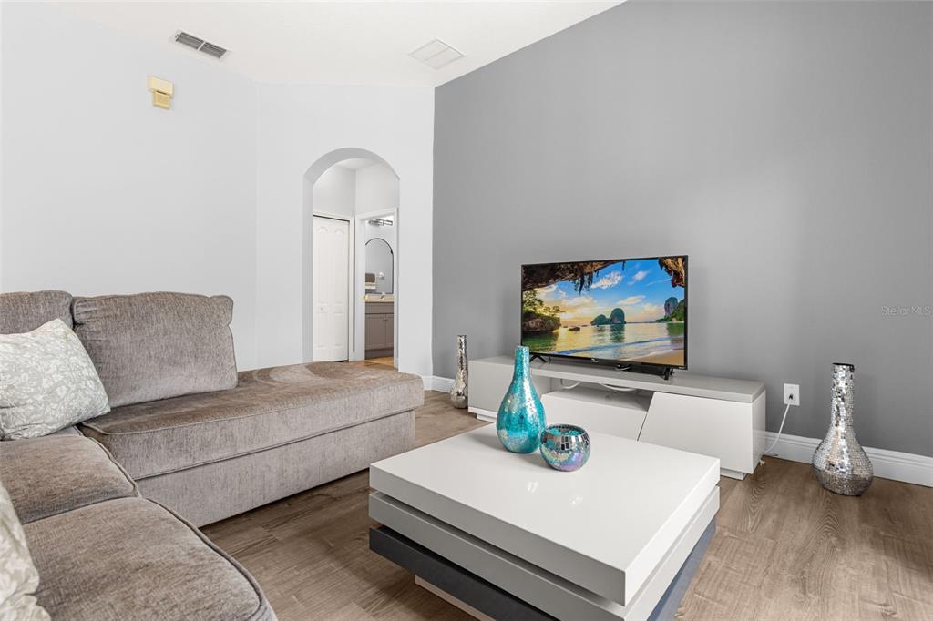 A living room features a gray sectional sofa, a white coffee table, and a television — 2026 ESTANCIA CIRCLE UNIT A, KISSIMMEE, FL