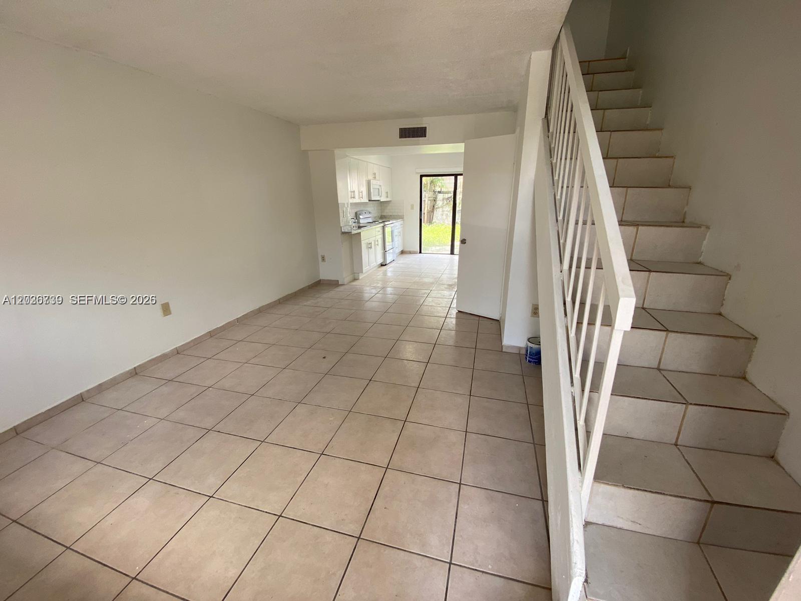 An open living area with tile floors leads to a kitchen and a staircase — 1813 SW 107th Ave # 2402, Miami FL 33165, MIAMI, FL