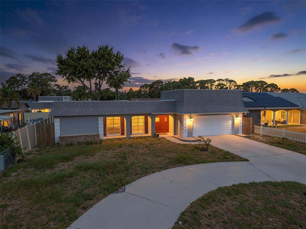 A single-story house with a gray exterior, a red front door, and a two-car garage — 3543 ROCKAWAY DRIVE, HOLIDAY, FL