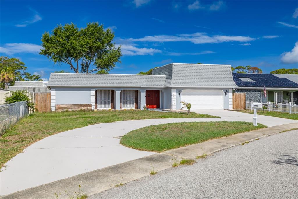 A single-story house with a gray exterior, a large driveway, and a two-car garage — 3543 ROCKAWAY DRIVE, HOLIDAY, FL