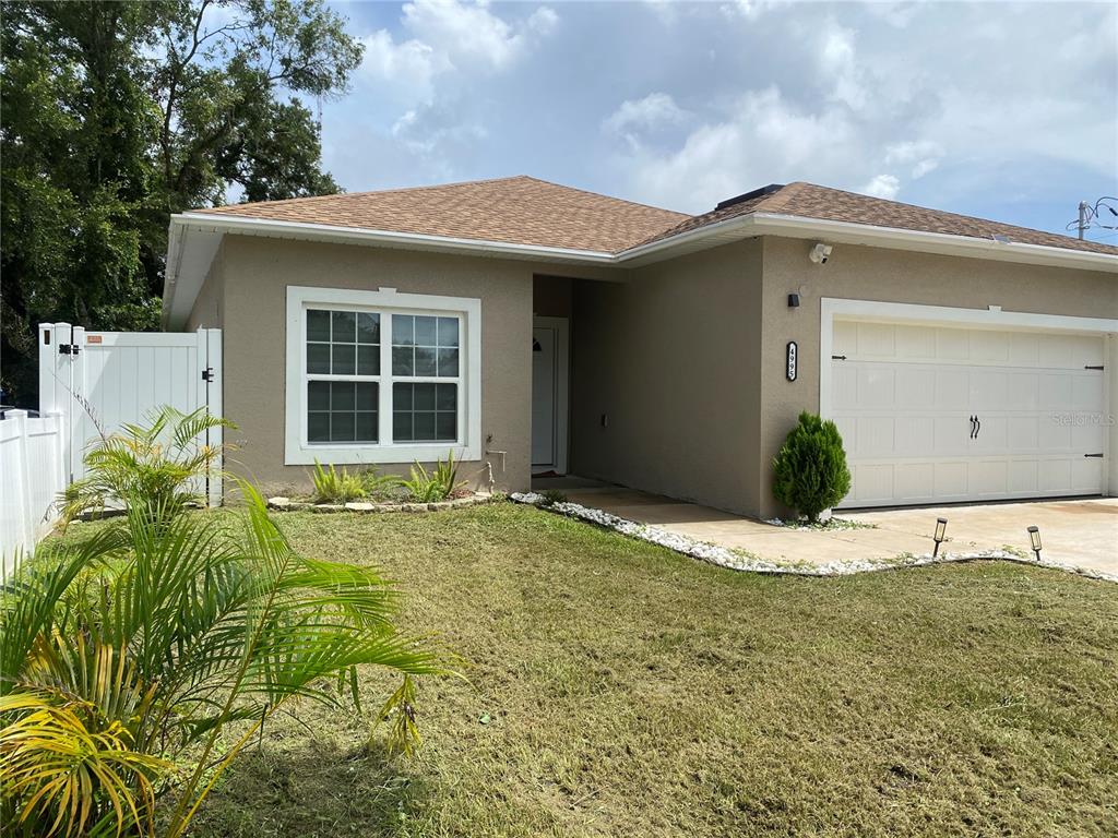 A single-story house with a tan stucco exterior, a two-car garage, and a front lawn — 4995 MERCER STREET, ORLANDO, FL