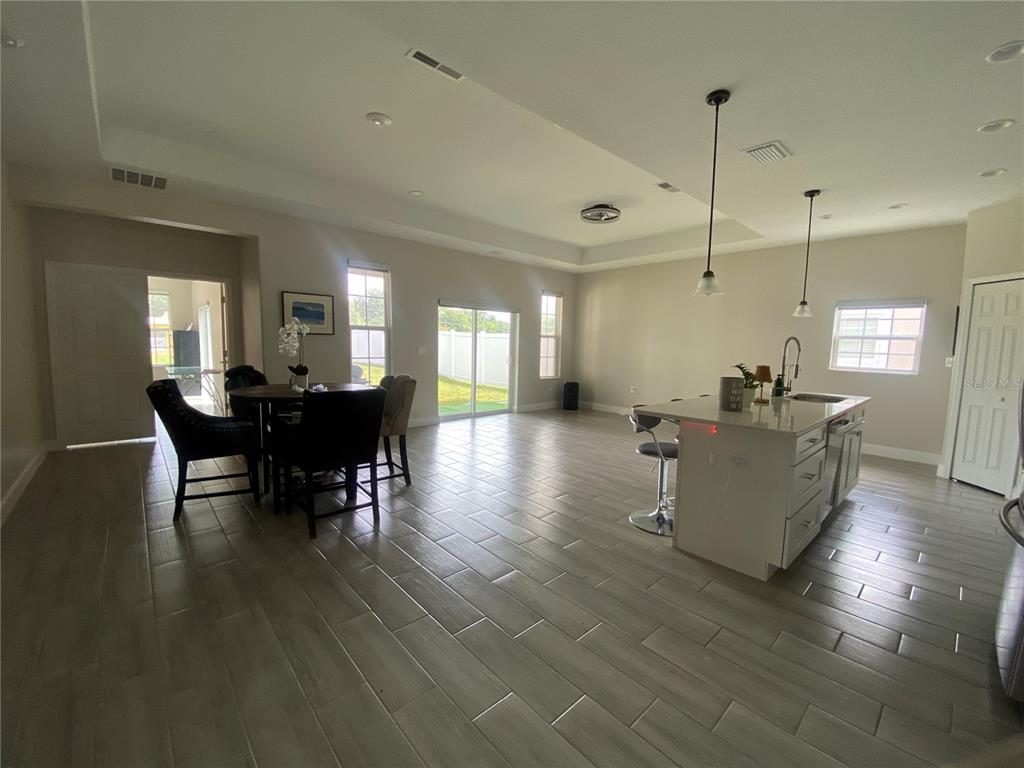 An open-concept kitchen and dining area features tile flooring, a center island, and sliding doors — 4995 MERCER STREET, ORLANDO, FL