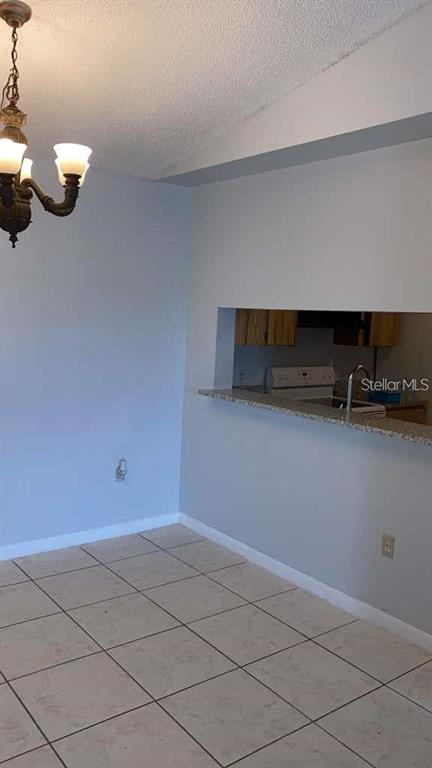 A dining area with tile flooring and a chandelier opens to a kitchen pass-through window — 5214 VIA HACIENDA CIRCLE UNIT A306, ORLANDO, FL
