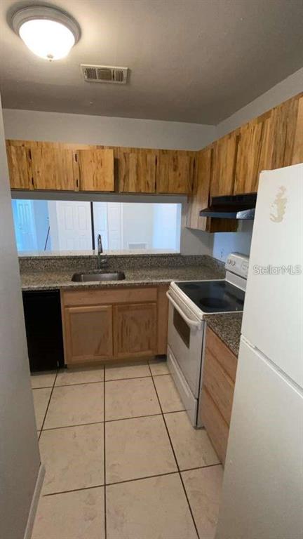 A kitchen features light wood cabinets, granite countertops, tile flooring, and a white refrigerator — 5214 VIA HACIENDA CIRCLE UNIT A306, ORLANDO, FL