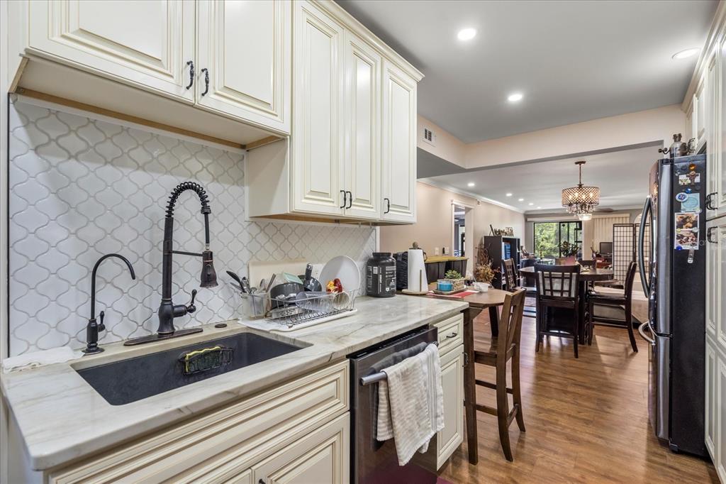 A kitchen with white cabinets, a dark sink, marble countertops, and a view into the dining — 4101 FAIRVIEW VISTA POINT UNIT 130, ORLANDO, FL