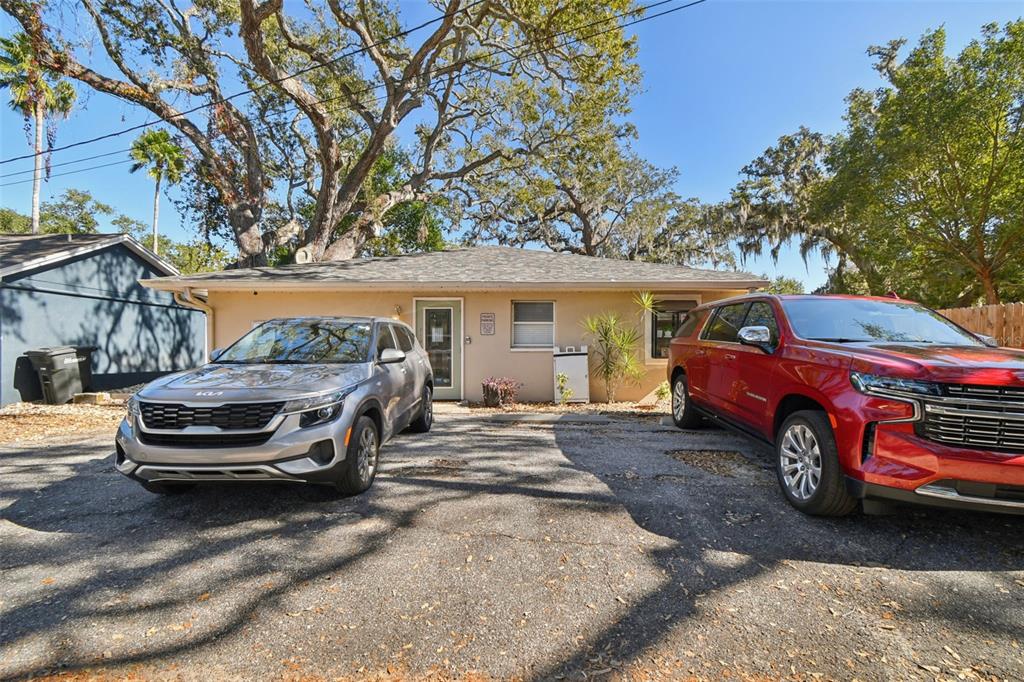 A single-story house with a tan exterior sits behind two parked cars on asphalt — 108 4TH AVENUE S, SAFETY HARBOR, FL