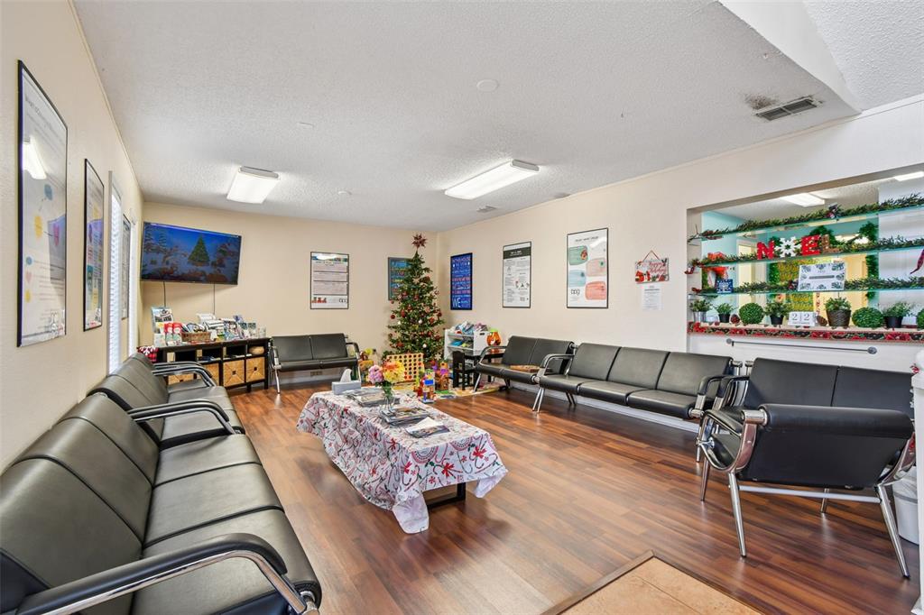 A waiting room features black leather chairs, wood-look flooring, a Christmas tree, and wall posters — 108 4TH AVENUE S, SAFETY HARBOR, FL