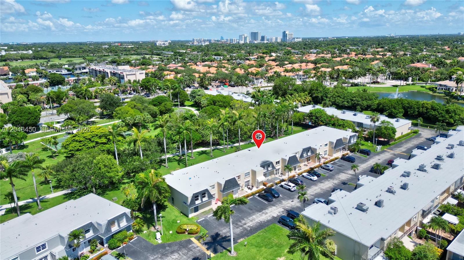 An aerial view shows a multi-story residential building with a parking lot and surrounding greenery — 933 NE 24th Ave # 169, Hallandale Beach FL 33009, HALLANDALE BEACH, FL