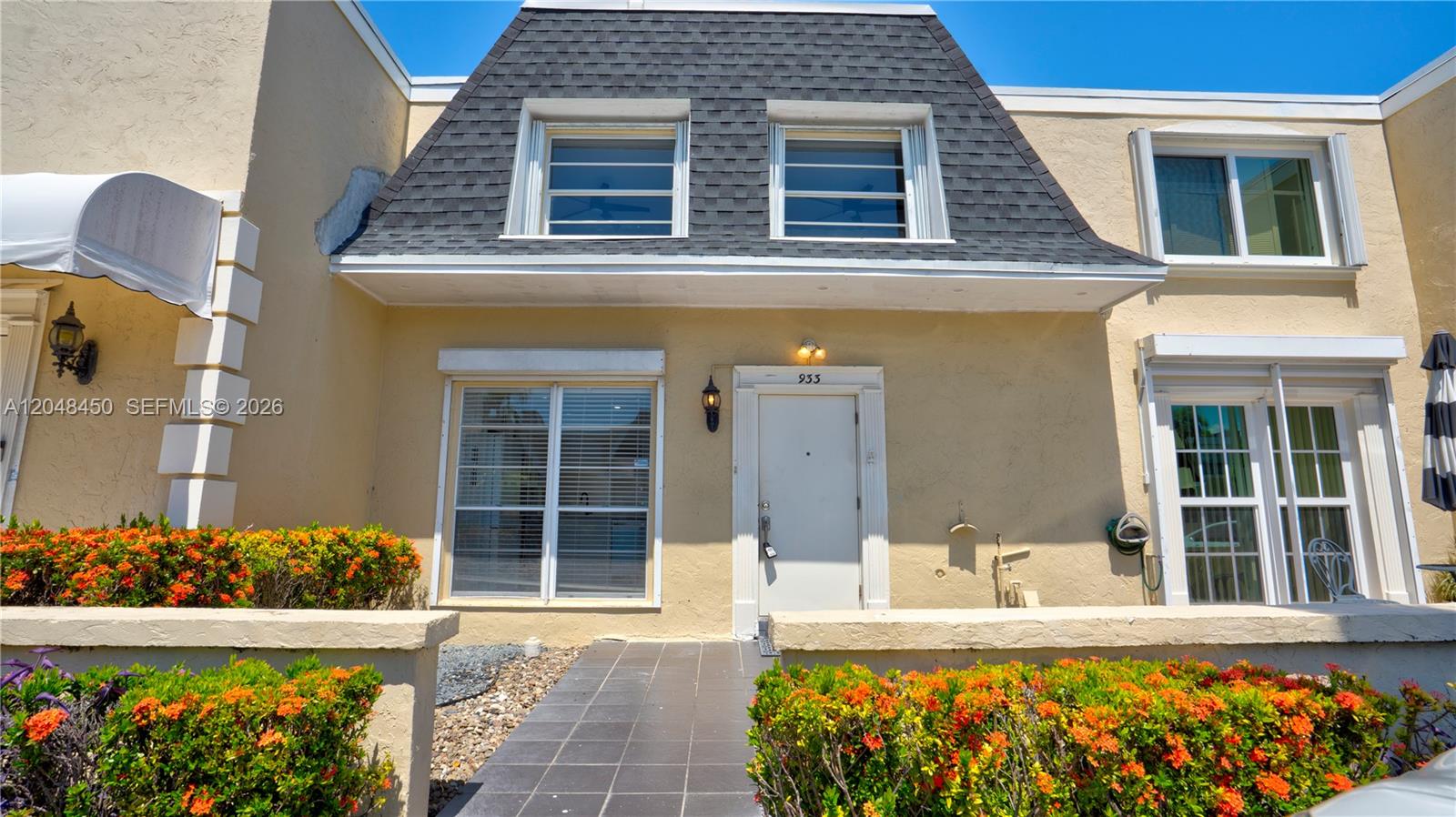 A two-story townhouse exterior features a mansard roof, beige stucco walls, and a front walkway — 933 NE 24th Ave # 169, Hallandale Beach FL 33009, HALLANDALE BEACH, FL