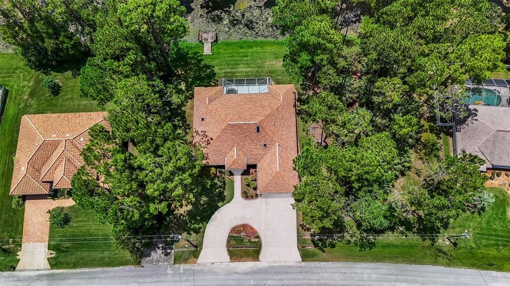 An aerial view shows a house with a brown roof, circular driveway, and surrounding trees — 73 WATERS DRIVE, PALM COAST, FL