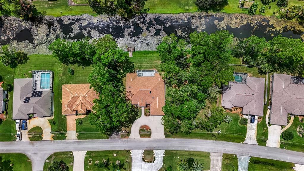 An aerial view shows several suburban houses with swimming pools and driveways along a canal — 73 WATERS DRIVE, PALM COAST, FL