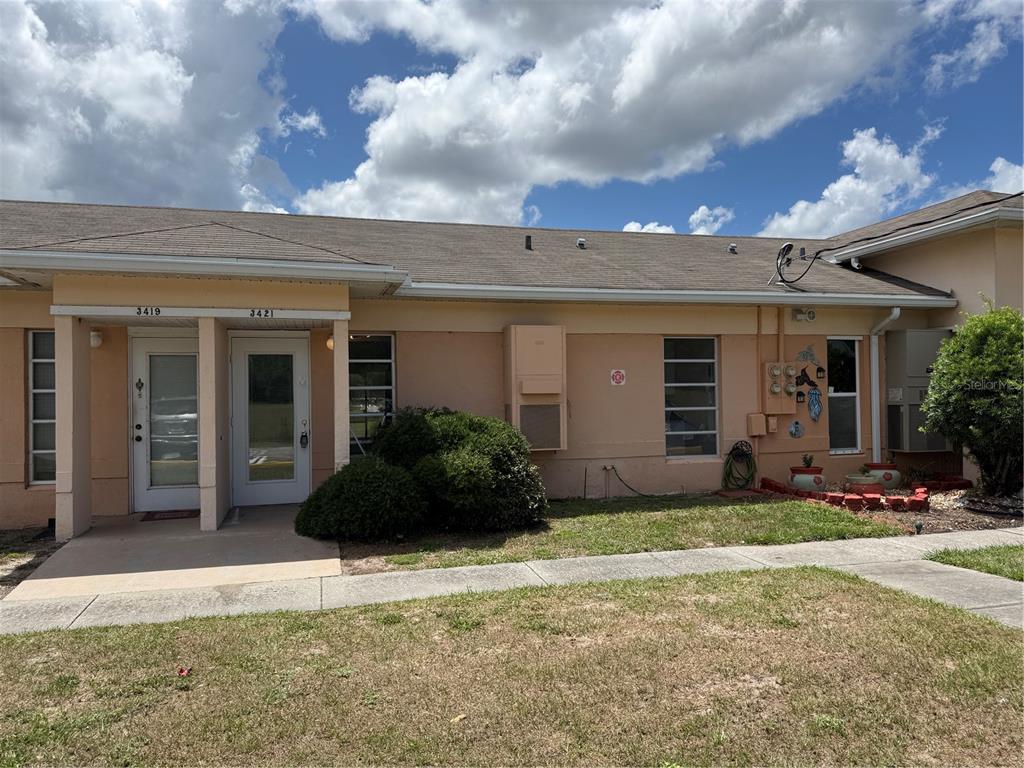 A single-story duplex building with peach-colored stucco walls and two front entry doors — 3421 CLUB CIRCLE, LAKESHORE, FL