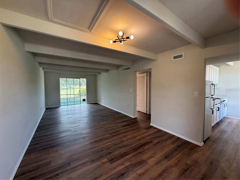 An open living area features wood-look flooring, exposed ceiling beams, and a sliding glass door — 3421 CLUB CIRCLE, LAKESHORE, FL