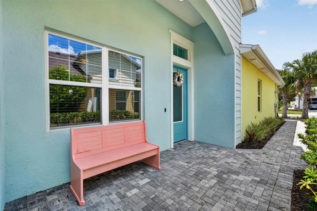 A pastel-colored house exterior features a pink bench on a stone-paved patio — 408 LOST SHAKER WAY, DAYTONA BEACH, FL