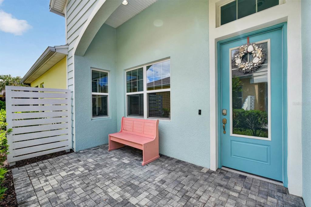 A light blue house exterior features a paved patio, a pink bench, and a teal door — 408 LOST SHAKER WAY, DAYTONA BEACH, FL