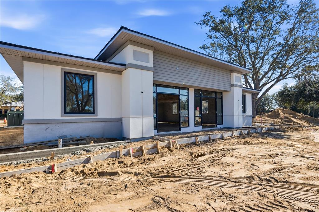A modern single-story building under construction features white stucco, gray siding, and large glass windows — 124 SOUTHERN RAILWAY UNIT 12, OAKLAND, FL
