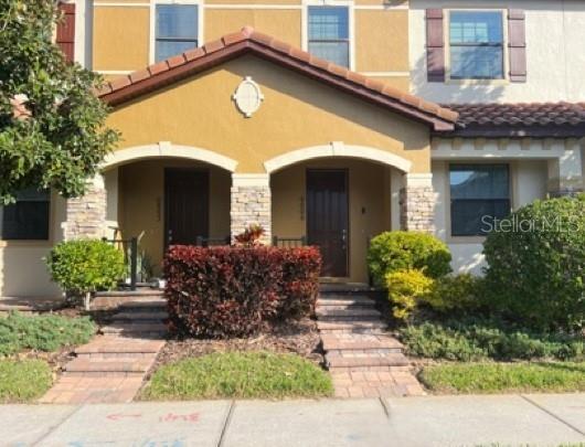 The exterior of a house features two brown doors, stone pillars, and landscaped bushes — 9999 EAGLE CREEK CENTER BOULEVARD, ORLANDO, FL
