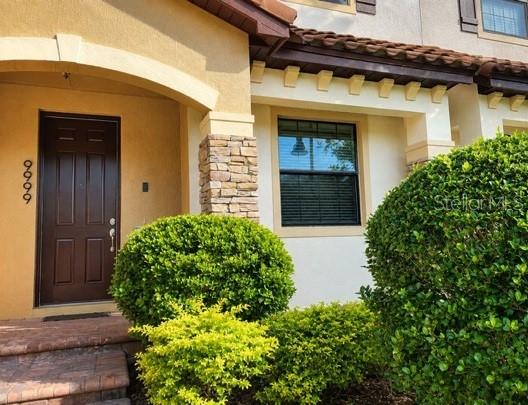 A brown front door with vertical numbers sits beside a window and green bushes — 9999 EAGLE CREEK CENTER BOULEVARD, ORLANDO, FL