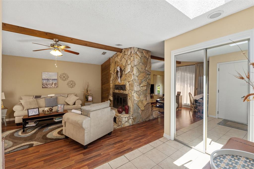 A living room with a stone fireplace, wood-look flooring, and a mirrored closet door — 2278 ARDENWOOD DRIVE, SPRING HILL, FL