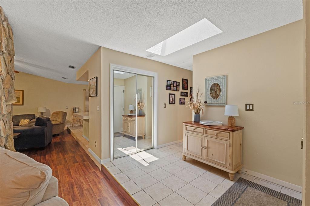 A tiled entryway features a mirrored closet, a wooden sideboard, and a skylight above — 2278 ARDENWOOD DRIVE, SPRING HILL, FL