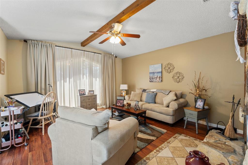 A living room features a vaulted ceiling with a wood beam, a ceiling fan, and furniture — 2278 ARDENWOOD DRIVE, SPRING HILL, FL