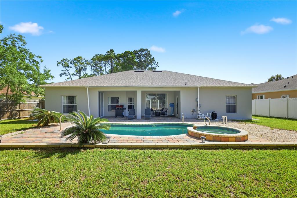 The backyard features a swimming pool, a hot tub, and a covered patio area — 49 BOTANY LANE, PALM COAST, FL