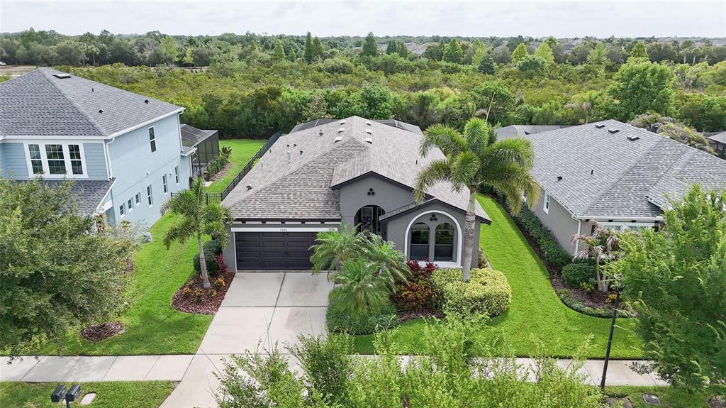 An aerial view shows a gray single-story house with a two-car garage and palm trees — 7020 OLD BENTON DRIVE, APOLLO BEACH, FL