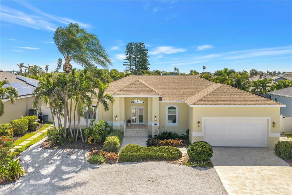 A single-story yellow house with a tan roof, palm trees, and a paved driveway — 343 8TH AVENUE N, TIERRA VERDE, FL