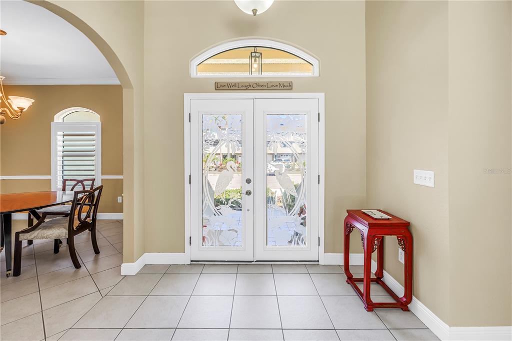 An entryway features tiled floors, a red accent table, and double doors with etched glass — 343 8TH AVENUE N, TIERRA VERDE, FL
