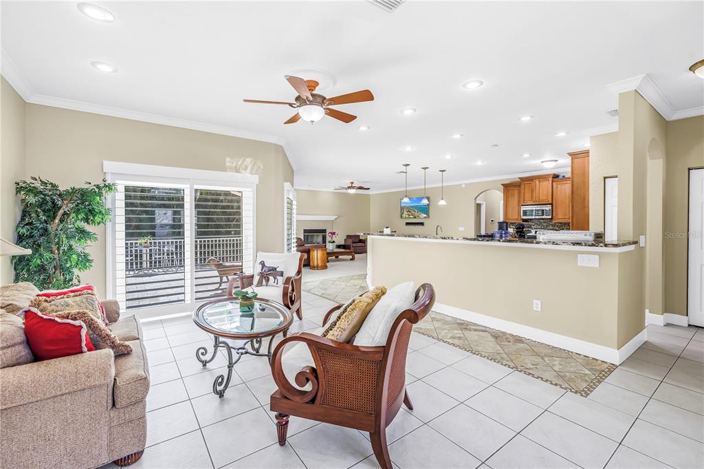 A living room with tile floors opens to a kitchen with a breakfast bar — 343 8TH AVENUE N, TIERRA VERDE, FL