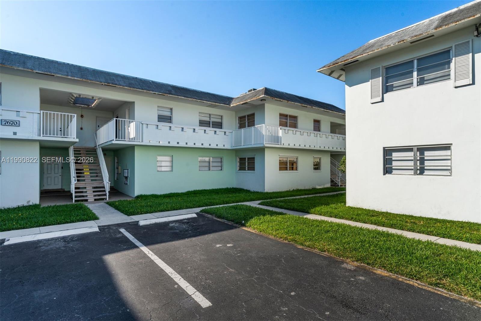 A two-story apartment building with a parking lot and green lawn in front — 7670 SW 82nd St # H117, Miami FL 33143, MIAMI, FL