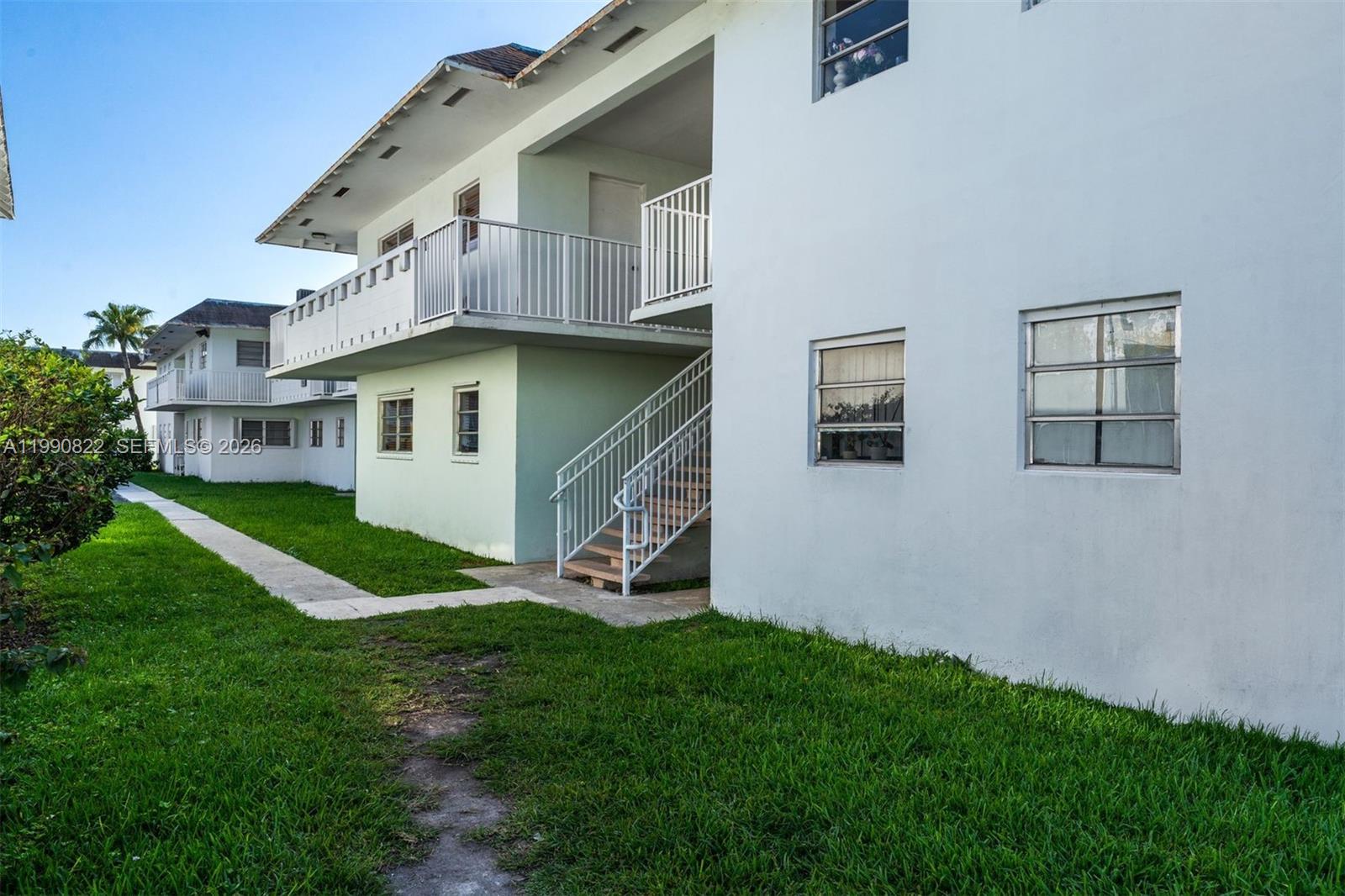 The exterior of a two-story apartment building features a white facade, stairs, and balconies — 7670 SW 82nd St # H117, Miami FL 33143, MIAMI, FL